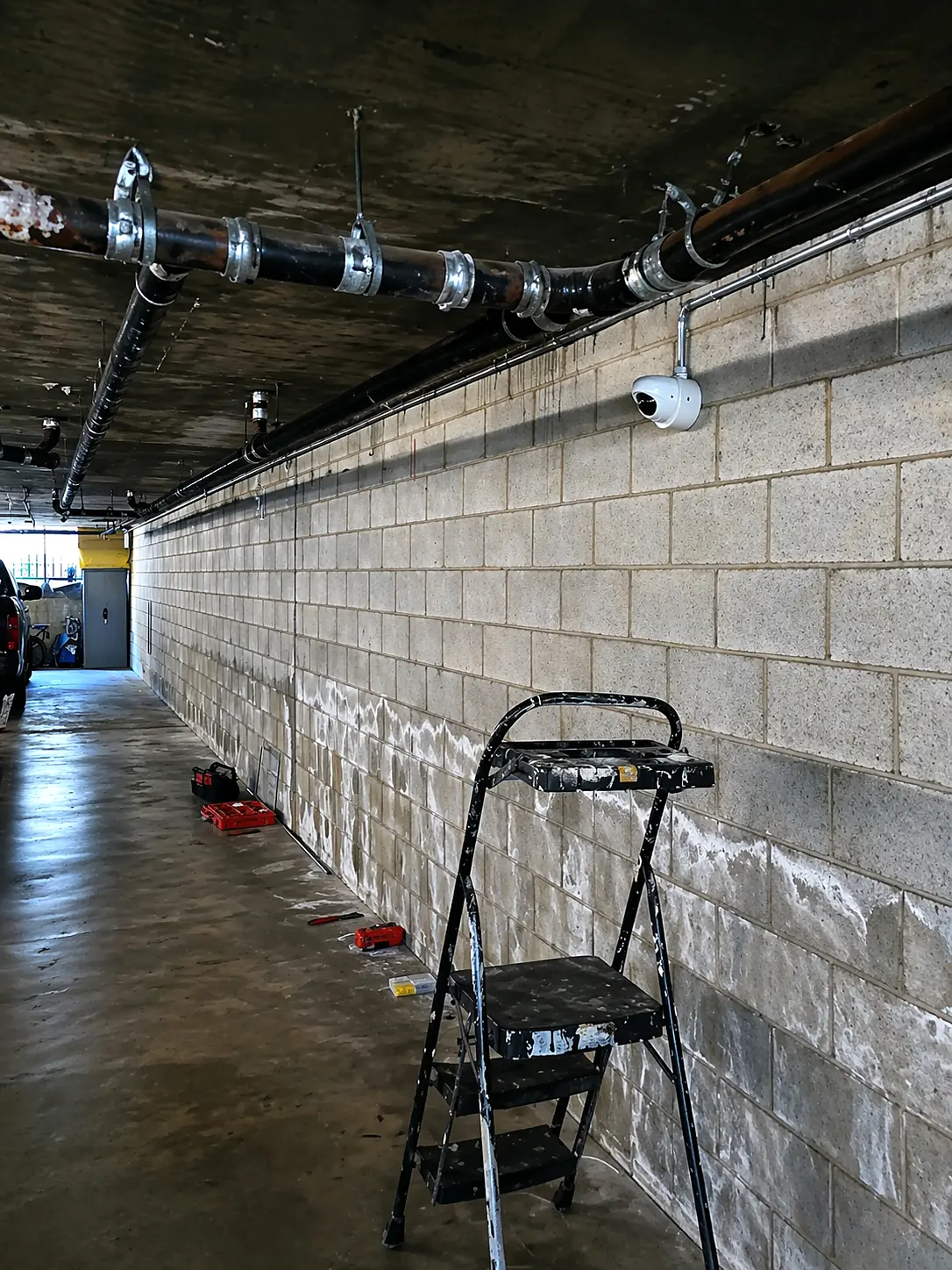 Security camera with surface-mounted conduit inside a Glendale apartment garage