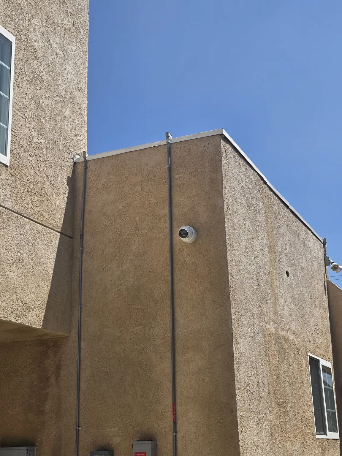 Security camera and protected conduit installed on an exterior wall in Pasadena