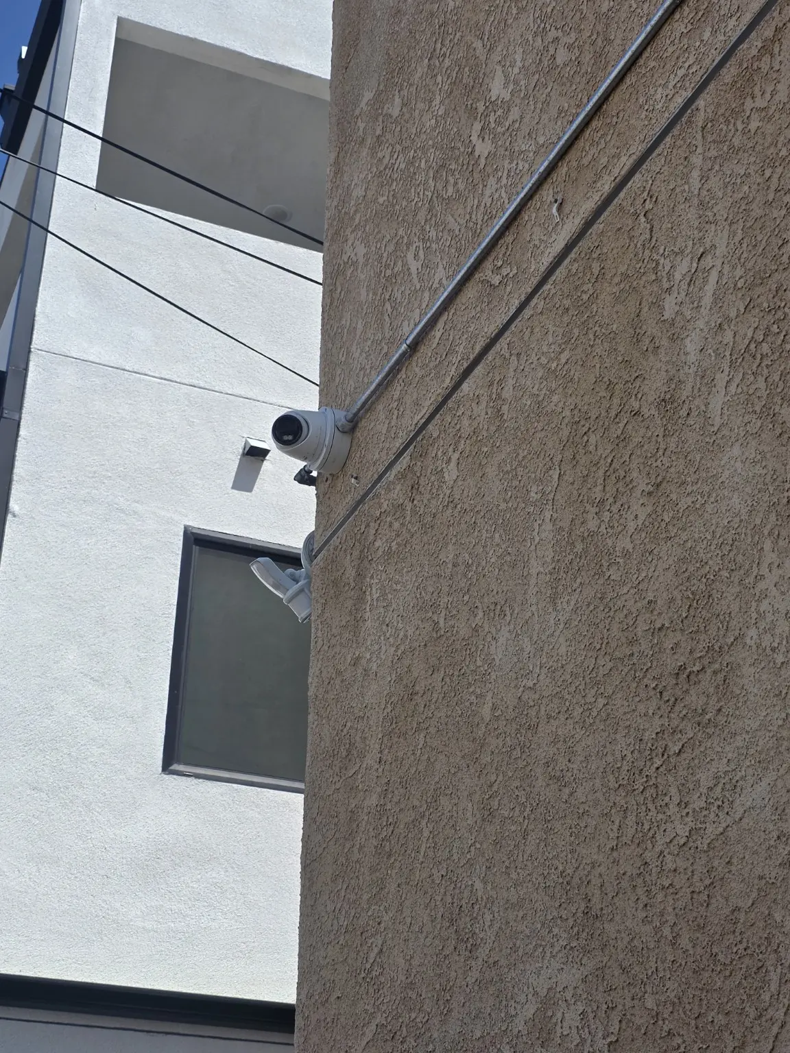 Exterior bullet camera with surface-mounted conduit on a Pasadena building