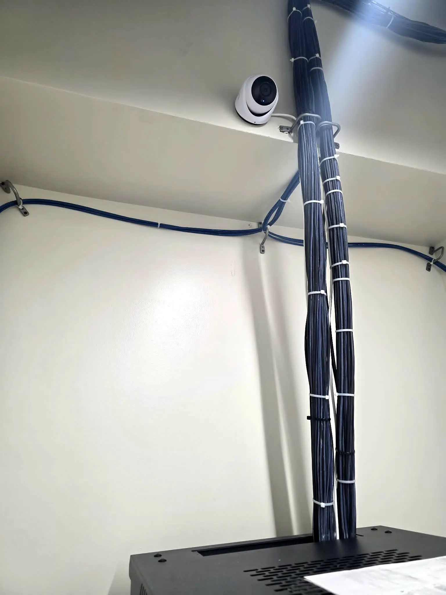 Security camera installed beside organized network cabling in the Tauro Technology server room